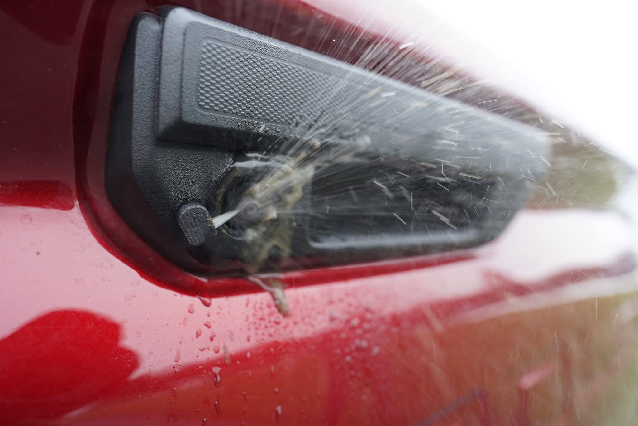 Backup camera being tested with water on a red vehicle