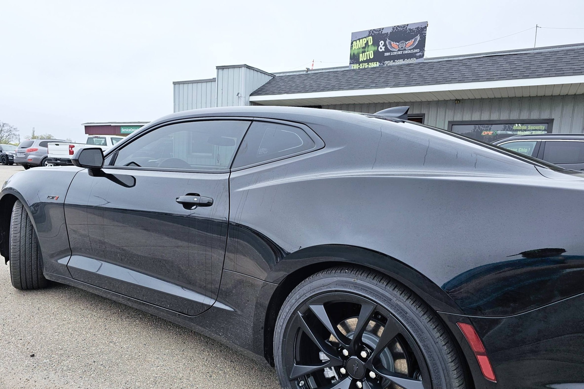 Black Chevrolet Camaro with tinted windows outside AMP'D AUTO