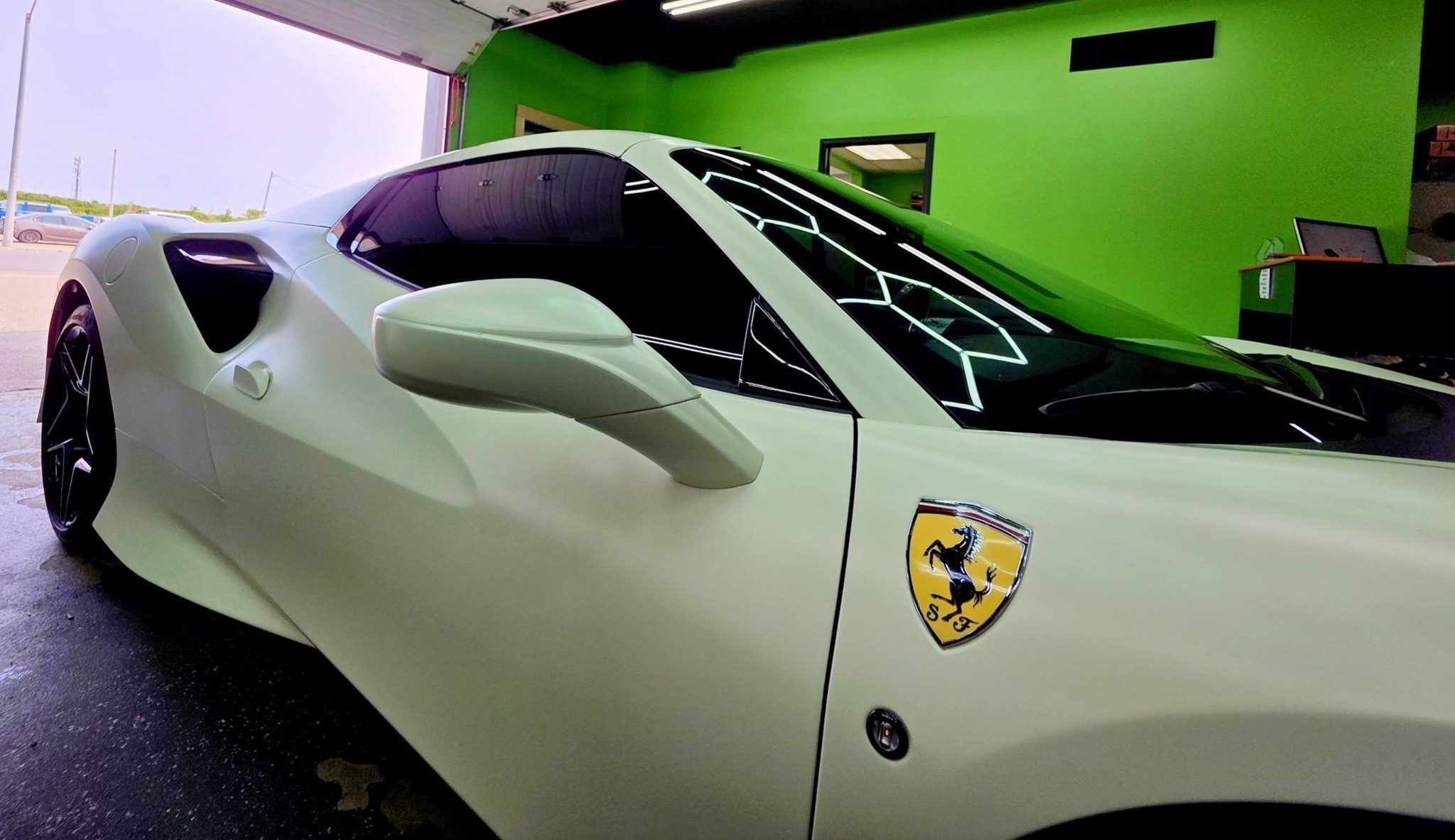 White Ferrari with dark window tint inside the AMP'D AUTO shop